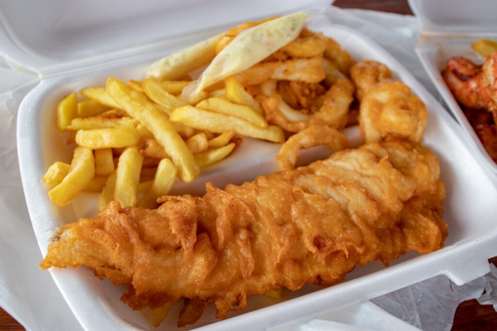 Authentic fish and chips made in a crispy batter served with golden fries and some delicious calamari. Fresh from a harbor shop in Hout Bay, Cape Town, South Africa. 